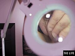 The big-titted brunette beauty explores her hairy pussy with a magnifying glass.