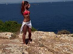 chick in bikini strips by cliff with clothes ripped