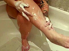 the seductive milf washes her feet seductively, showing off big tits and hairless body