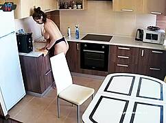 Big tits beauty cleans the kitchen topless, showing off pierced nipples.